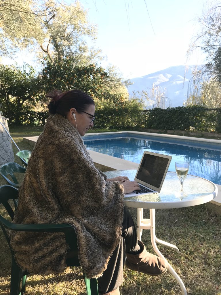 Blogger at work with a glass of obligatory New Year bubbles and a wrap against the chilly mountain air.